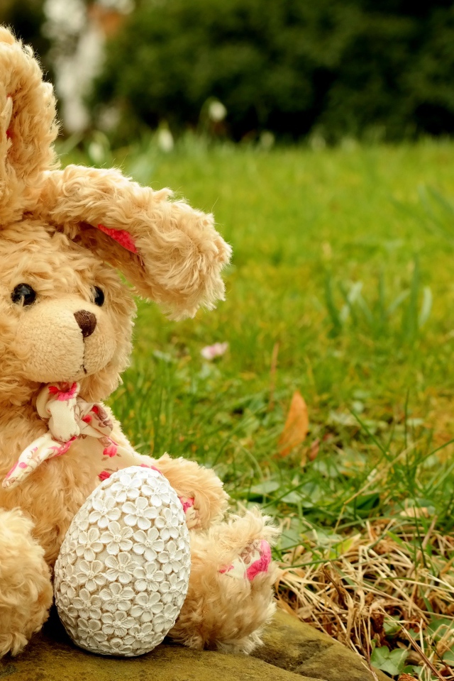 Игрушка заяц на камне в траве