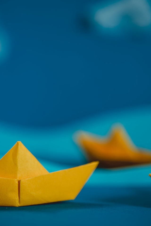 Желтые кораблики оригами на синем фоне