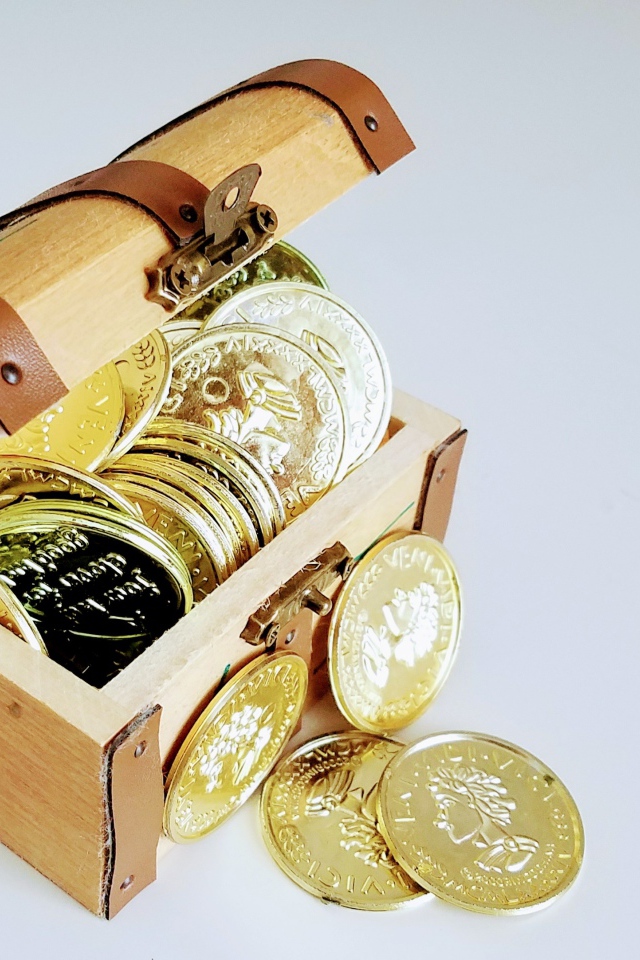 Золотые монеты в сундуке на сером фоне