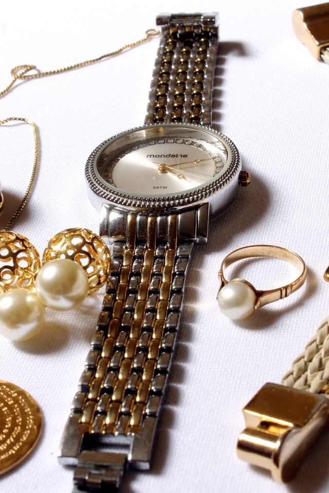 Наручные часы и золотые украшения на белом фоне