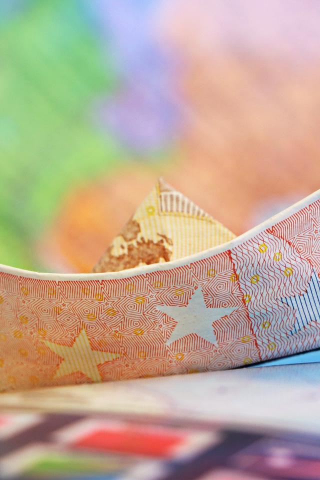 Кораблик из купюры евро на столе 