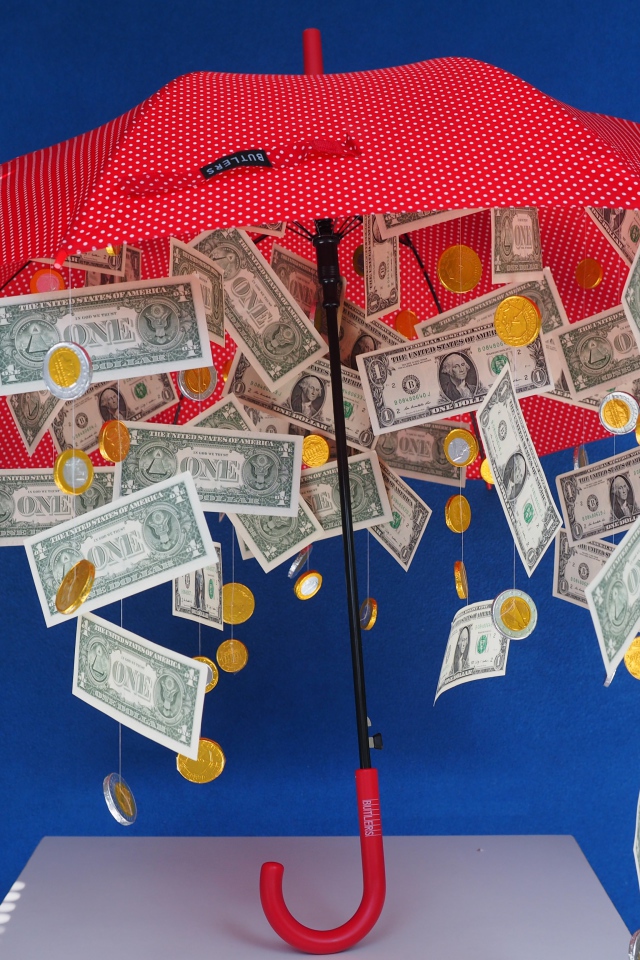 Доллары и монеты высыпаются из зонта на голубом фоне