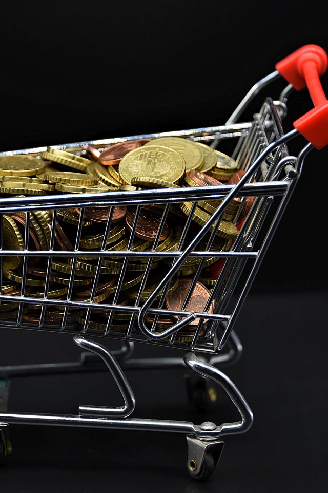 Железная тележка с монетами на черном фоне 