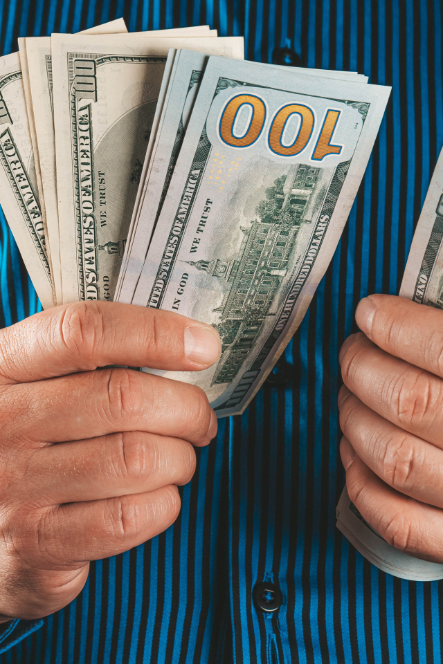 Мужчина считает сто долларовые купюры 