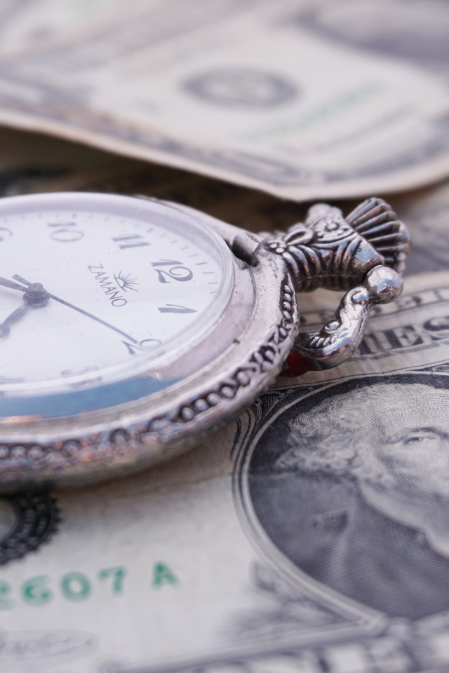 Карманные часы и доллары лежат на столе 