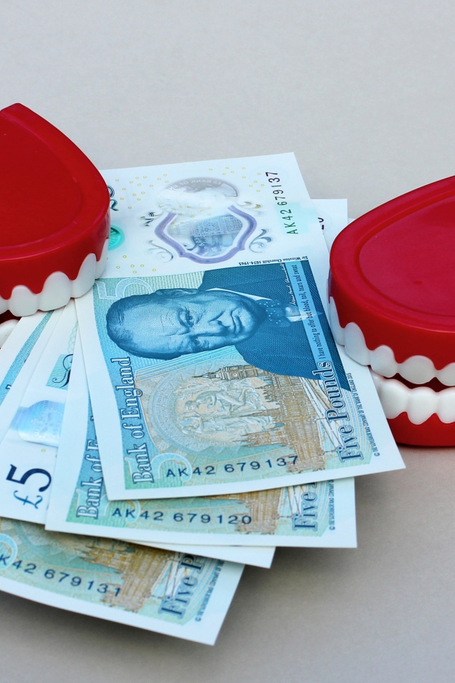 Два держателя денег в форме челюсти с купюрами на сером фоне