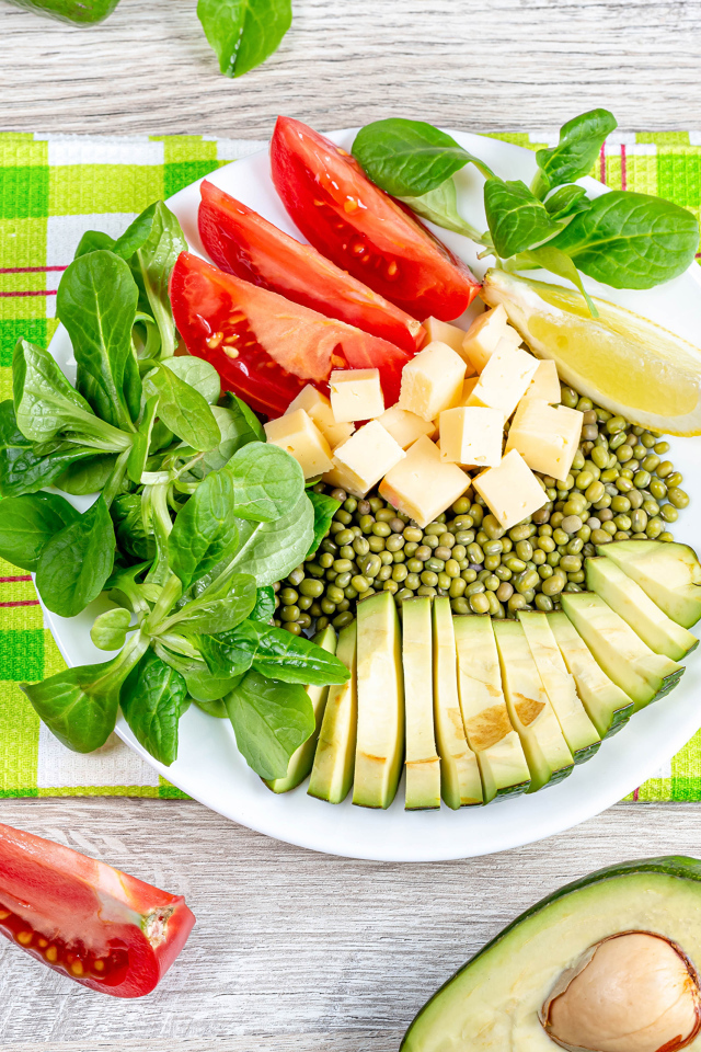 Аппетитные  свежие овощи с сыром и лимоном на тарелке 