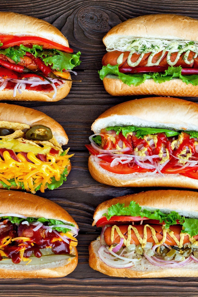 Аппетитные хот доги с разной начинкой на деревянном столе 