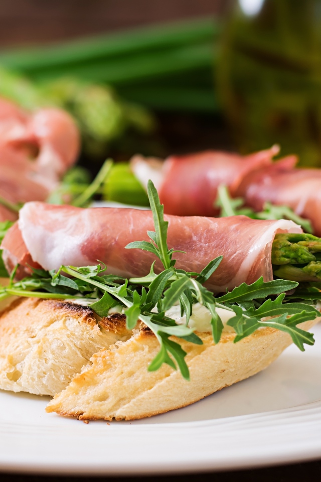 Рулетики с беконом и спаржей на тарелке с гренками