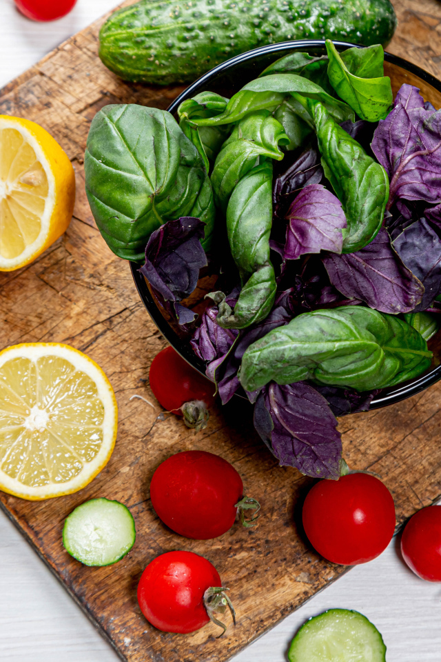 Базилик на столе с зеленью, помидорами и лимоном