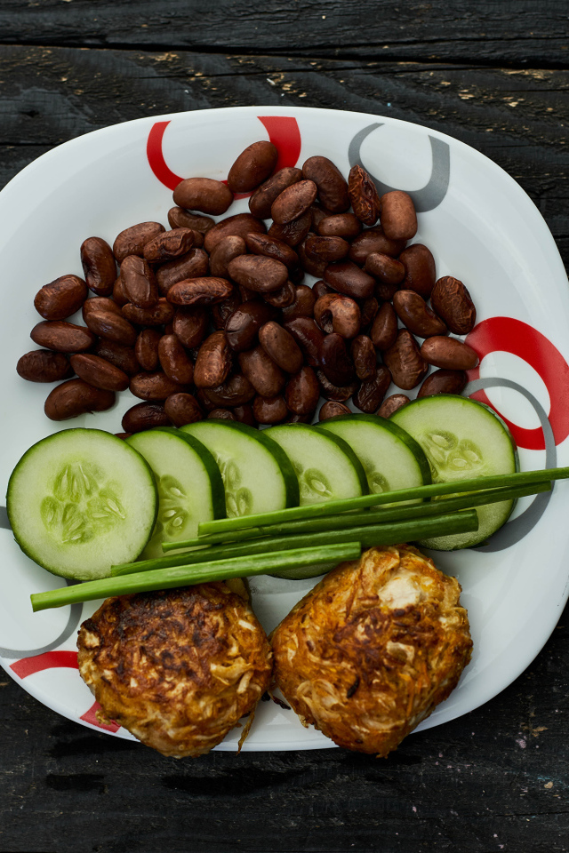 Фасоль на тарелке с оладьями и огурцами 