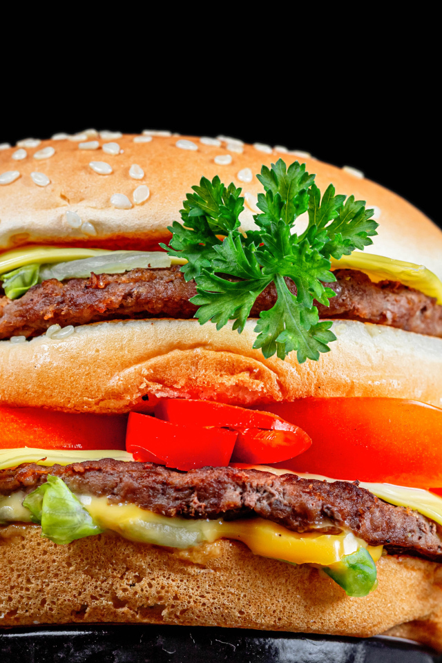 Большой гамбургер с котлетой на черном фоне