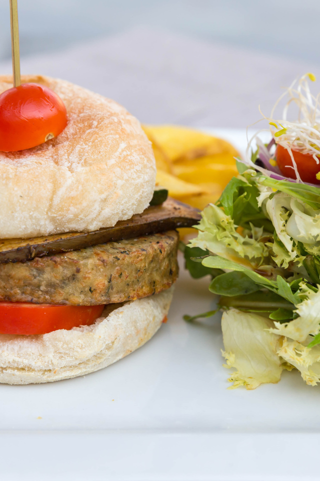 Большой гамбургер с салатом на столе 
