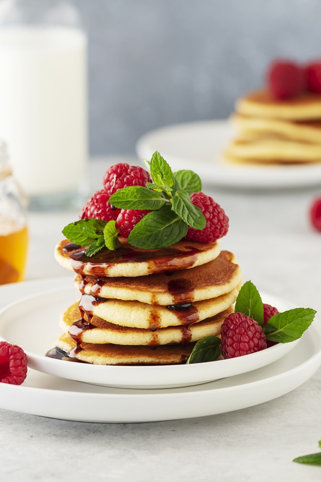 Румяные оладьи на тарелке с малиной и мятой 