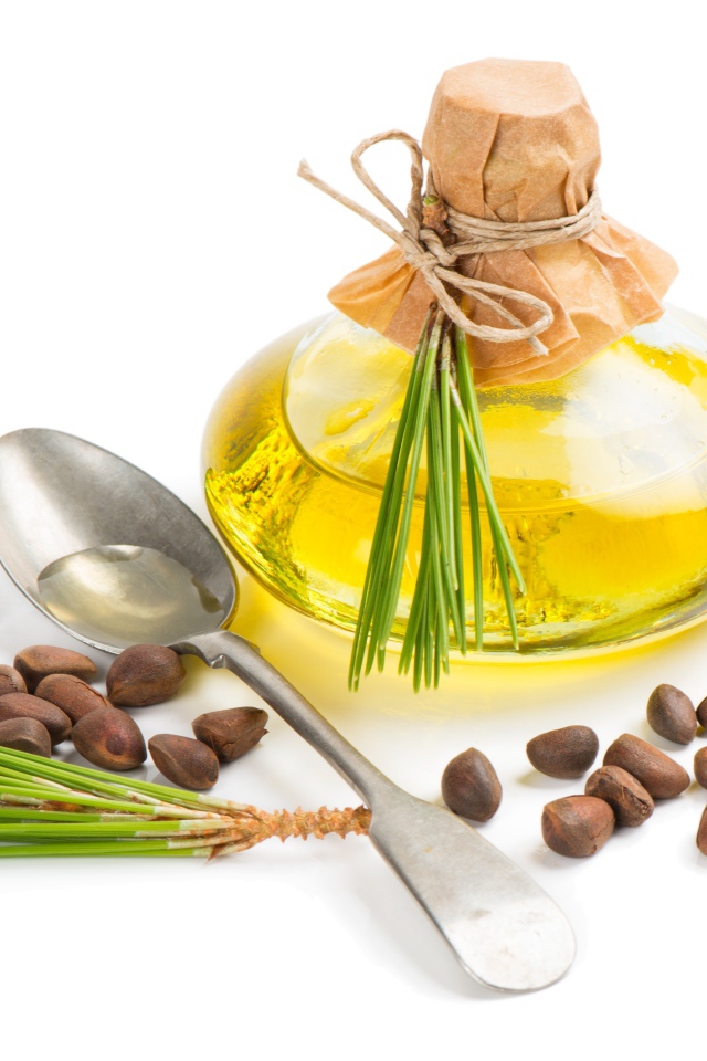 Кедровое масло на белом фоне с орехами и ложкой