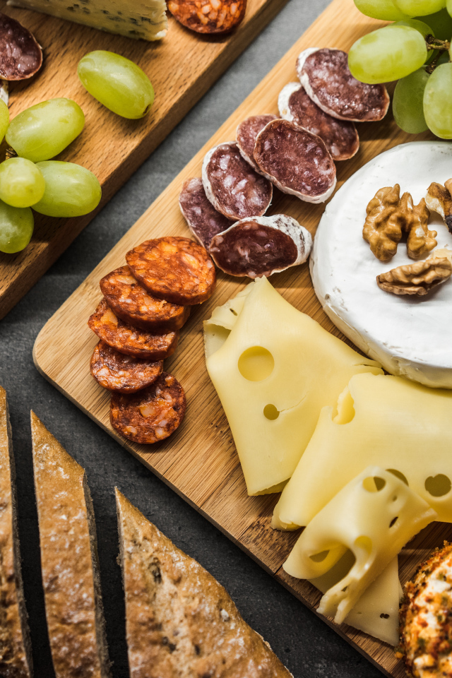 Сыр, колбаса, виноград и батон  на столе 