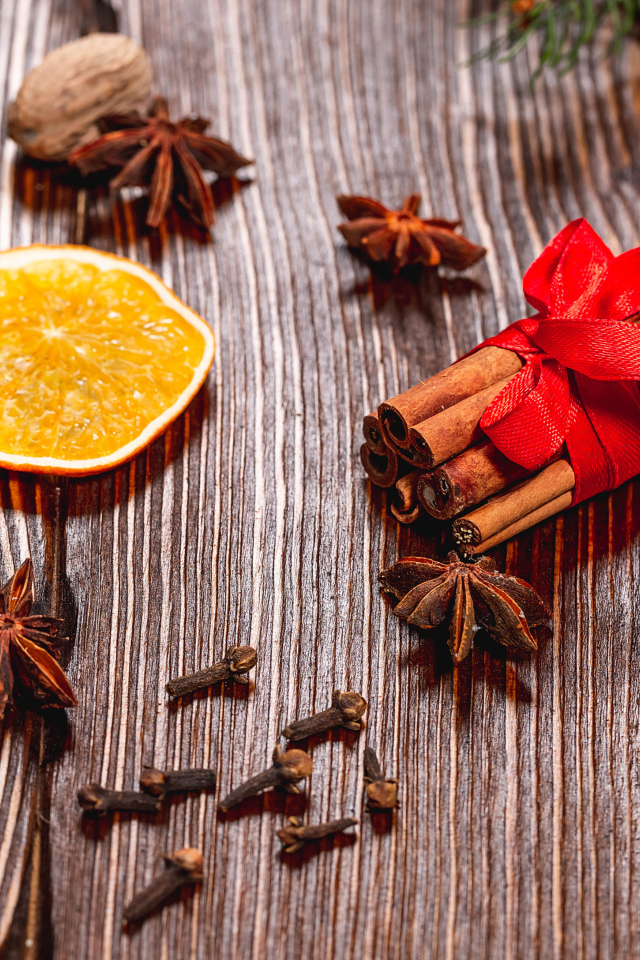 Корица на столе с орехами, бадьяном, сушеными апельсинами и гвоздикой