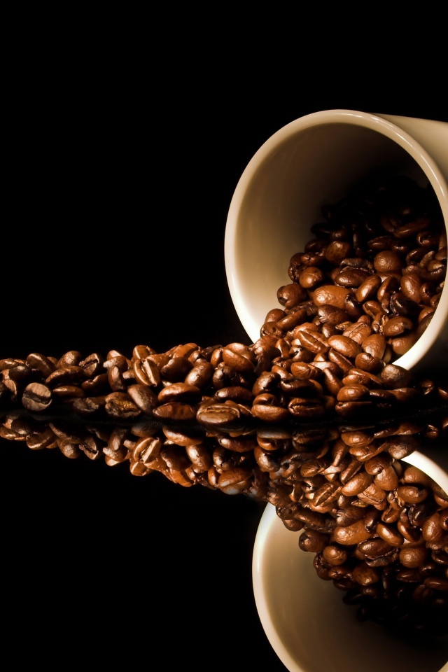 Кофейные зерна рассыпаны с белой кружки на стол