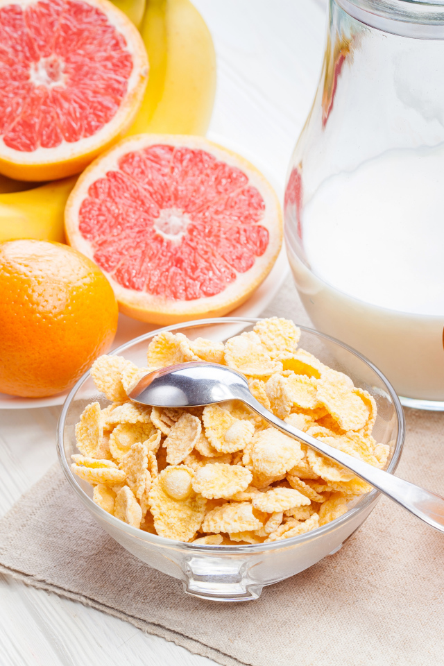 Кукурузные хлопья на столе с молоком, соком и свежими фруктами на завтрак