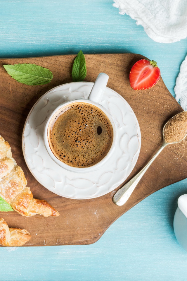 Чашка кофе на доске с клубникой и круассанами