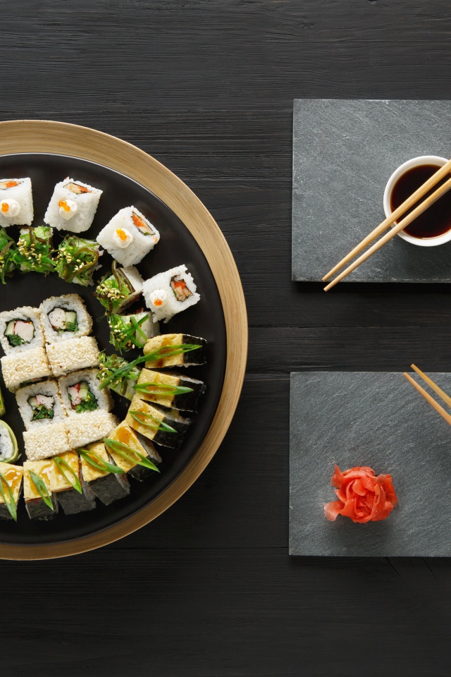 Вкусные  роллы на столе с соевым соусом и палочками 