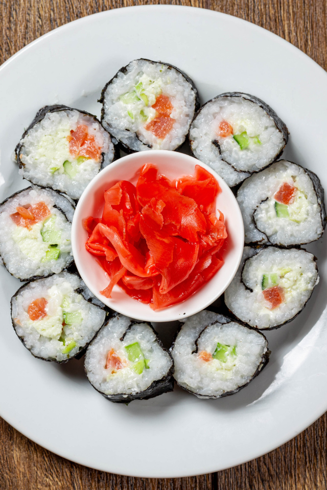 Вкусные суши на большой белой тарелке с имбирем