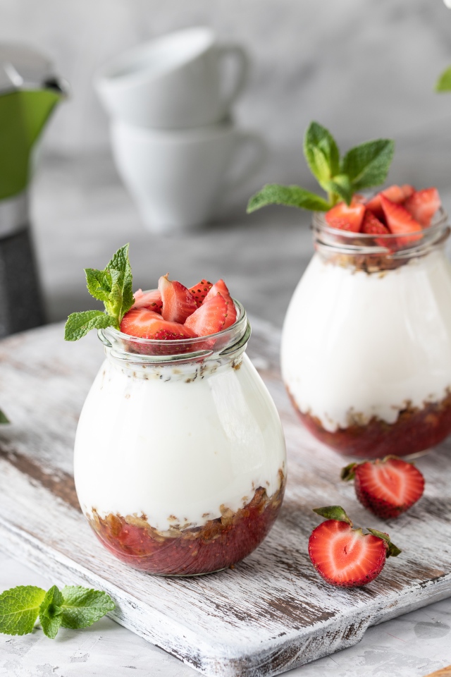 Десерт с йогуртом в банке с клубникой на столе цветами вишни 