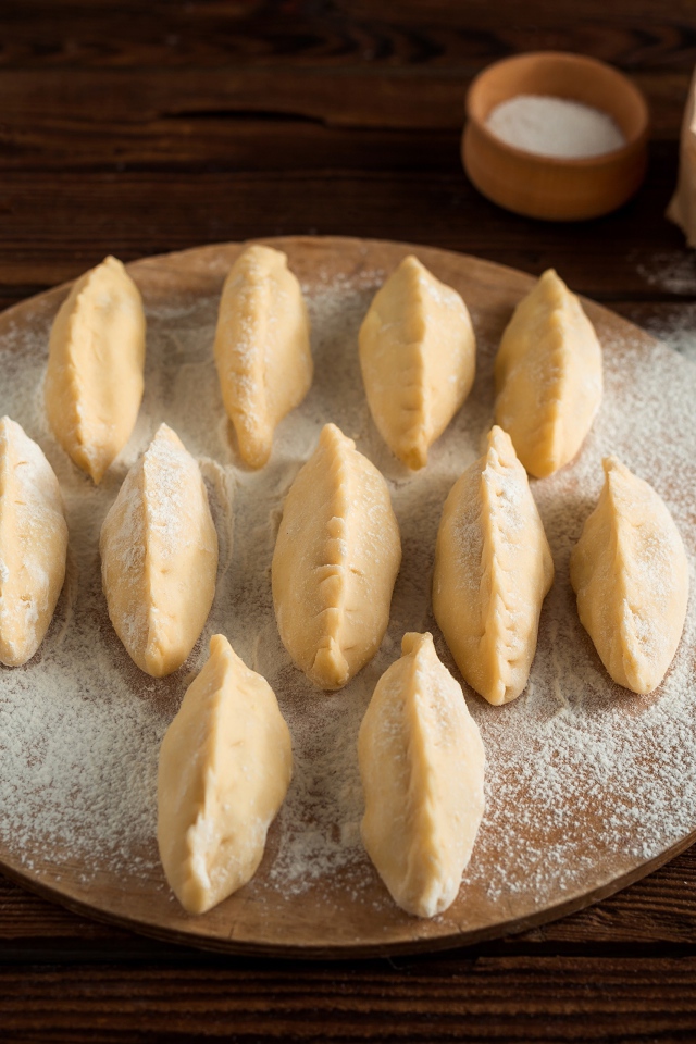 Вареники с картошкой на доске с мукой