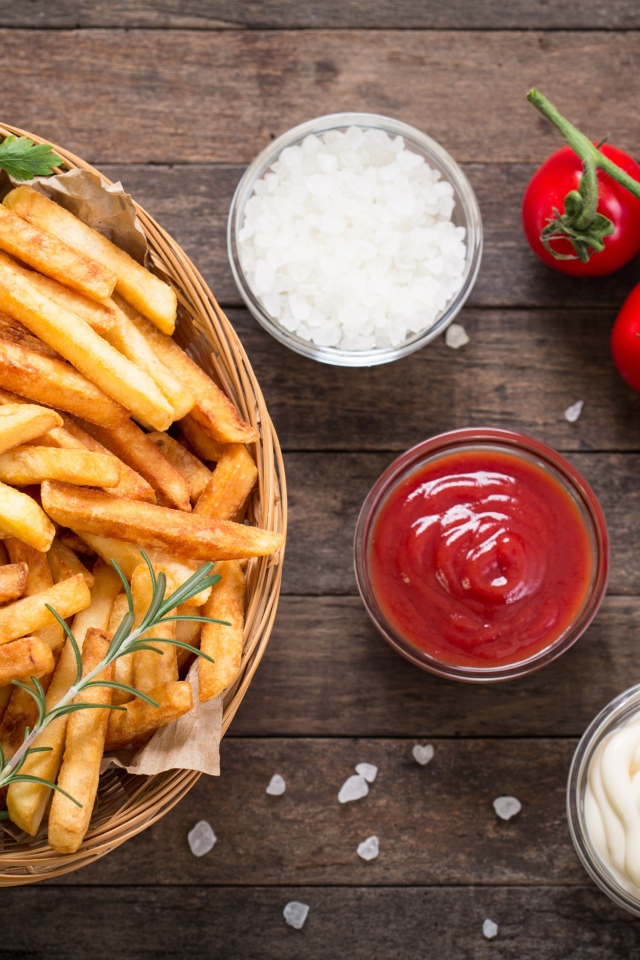 Картофель фри на столе соусом, солью и помидорами 