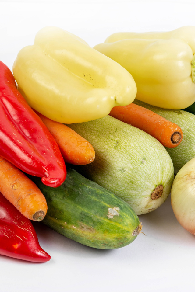 Свежие кабачки, огурцы, морковь, перец и лук на белом фоне