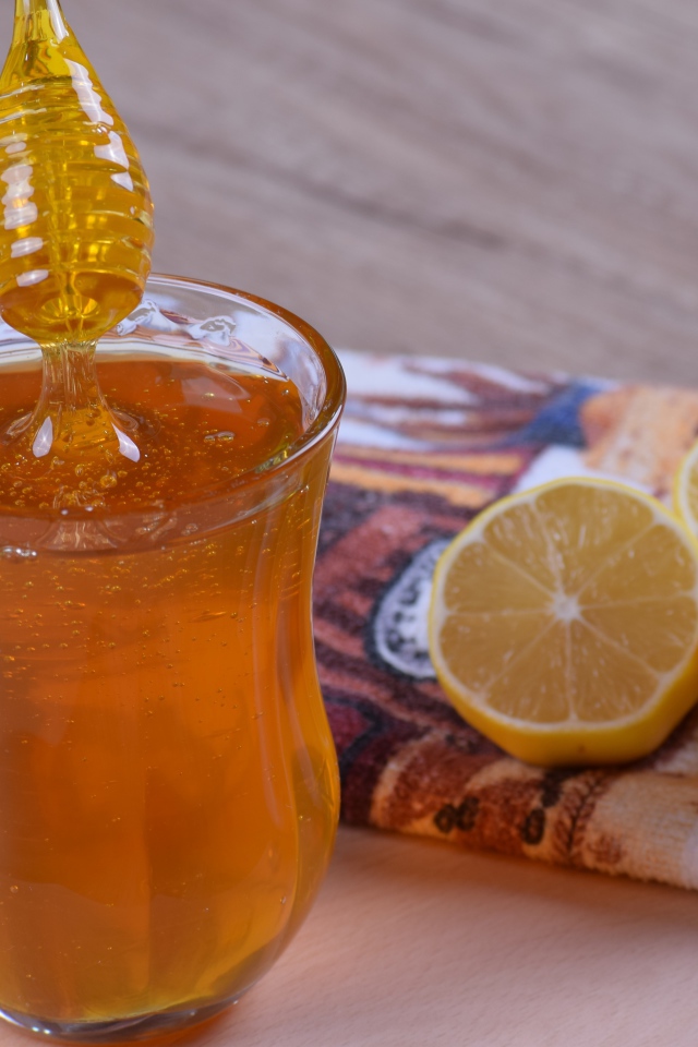 Glass mug with honey on the table with lemon