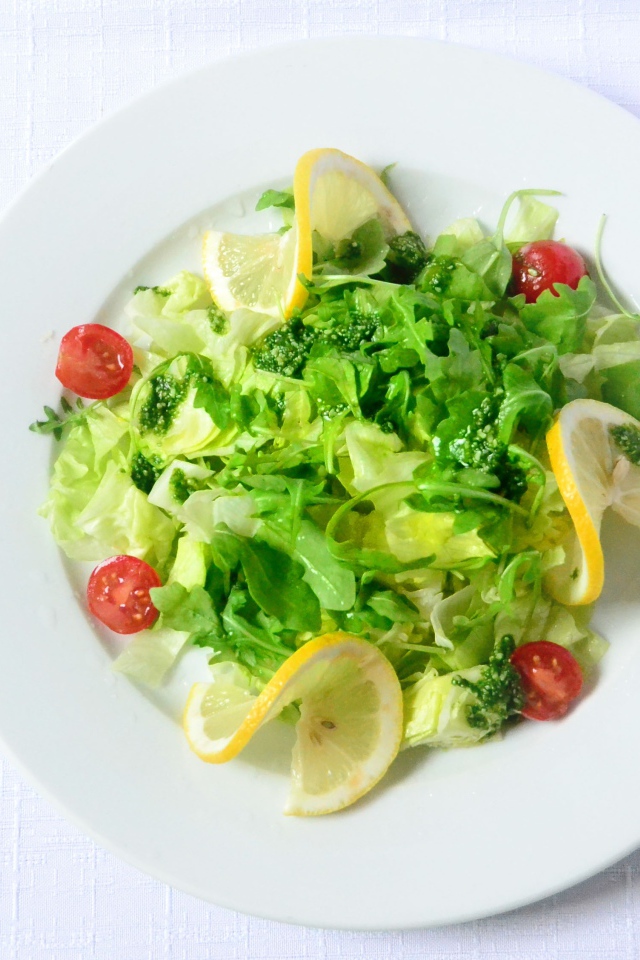 Салат из зелени с лимоном на белом фоне 