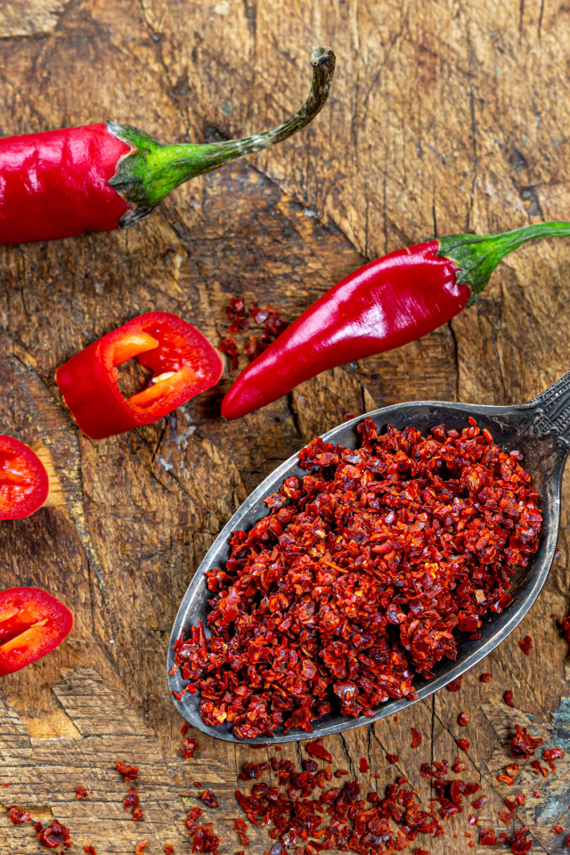 Молотый красный перец на ложке на столе 