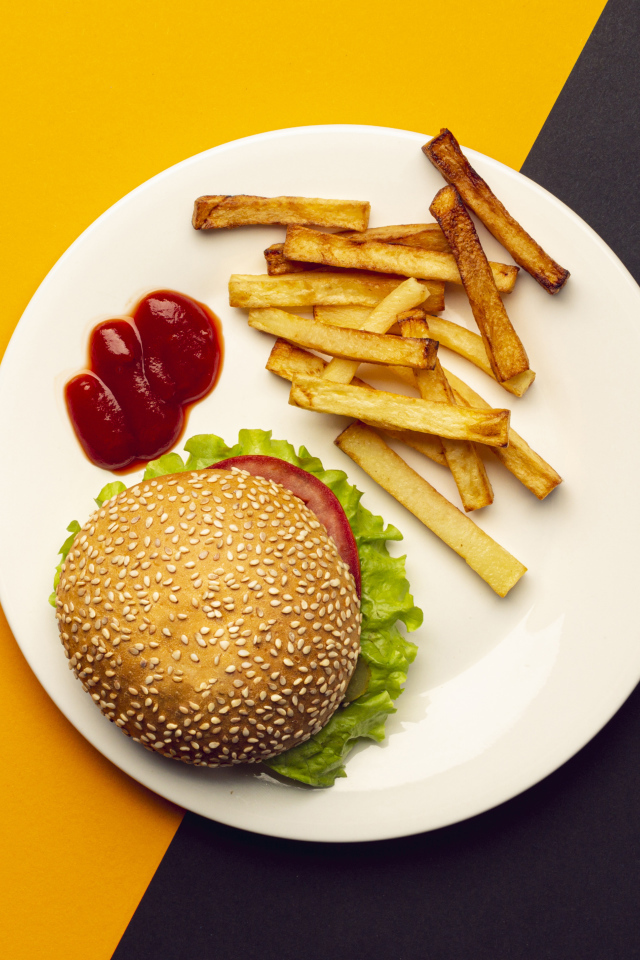 Гамбургер на белой тарелке с соусом и картофелем фри