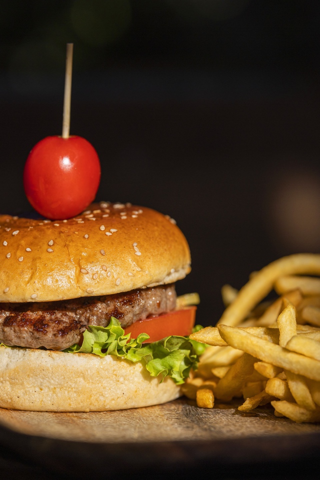 Гамбургер с помидором на доске с картофелем фри 