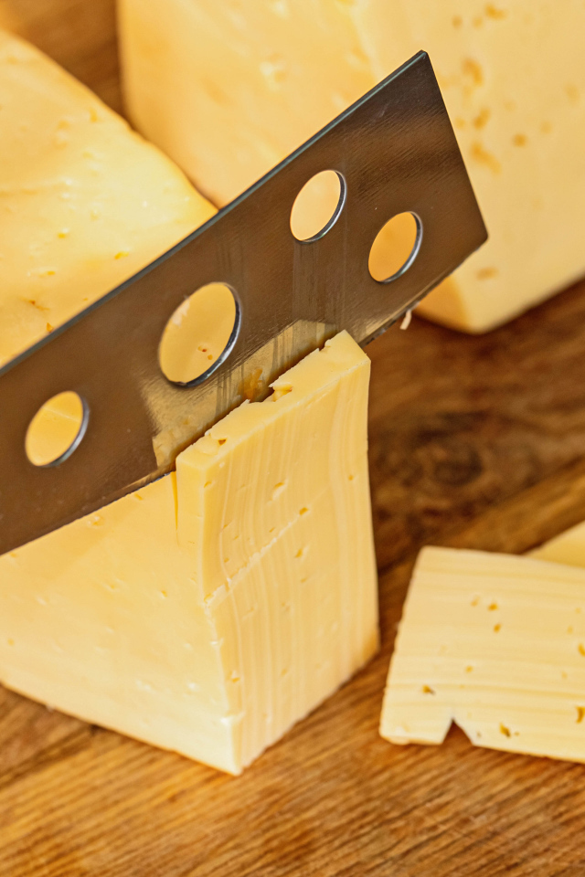 Твердый сыр с ножом на столе