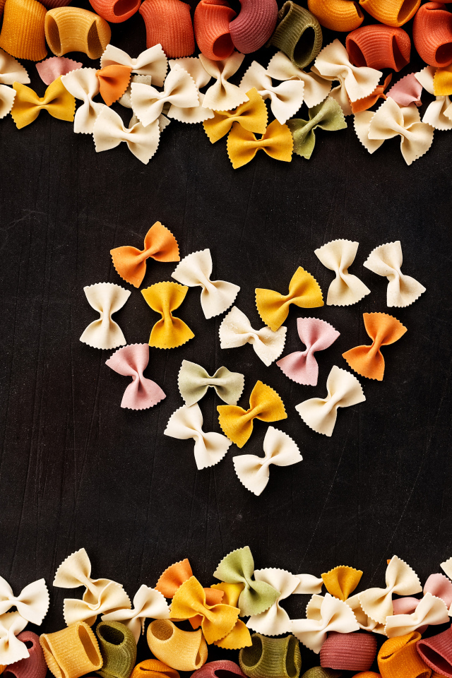 Сердце из разноцветных макарон на черном столе 