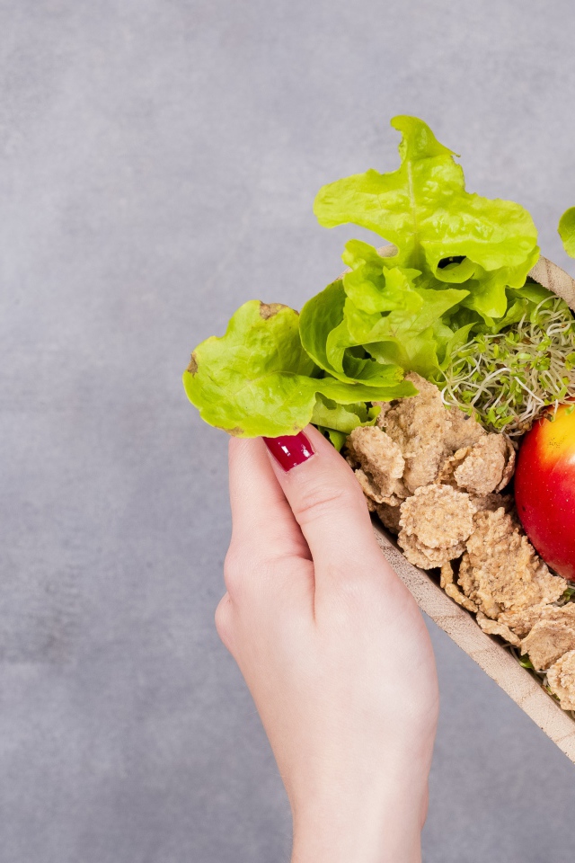 Коробка в форме сердца с яблоком и листьями салата 