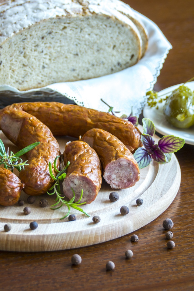 Домашняя колбаса на столе с хлебом и маринованными огурцами