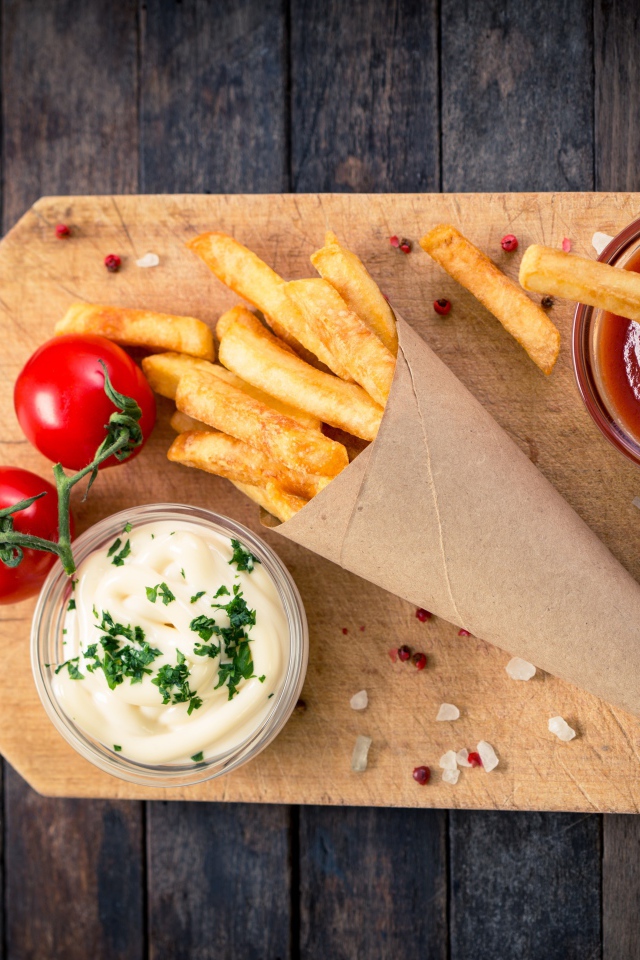 Кетчуп, соус и картофель фри на доске с помидорами