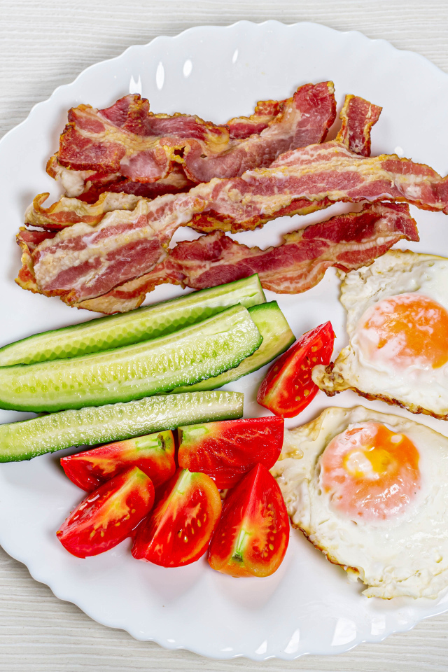 Большая белая тарелка с беконом, огурцами, помидорами и яичницей 