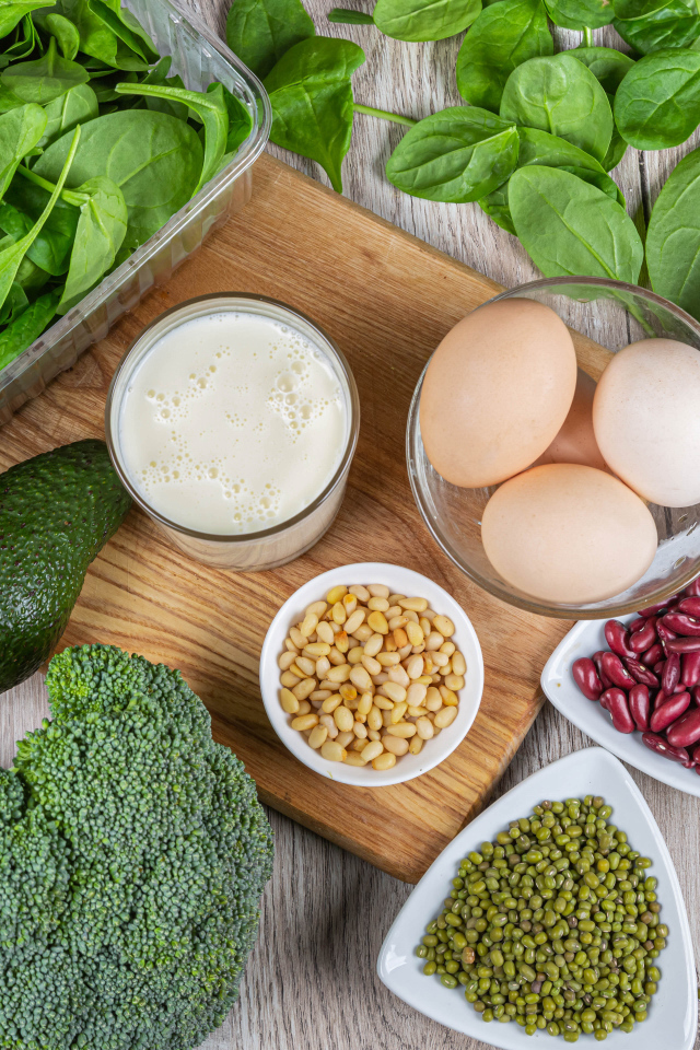 Бобовые, авокадо, базилик, яйца молоко и брокколи на столе