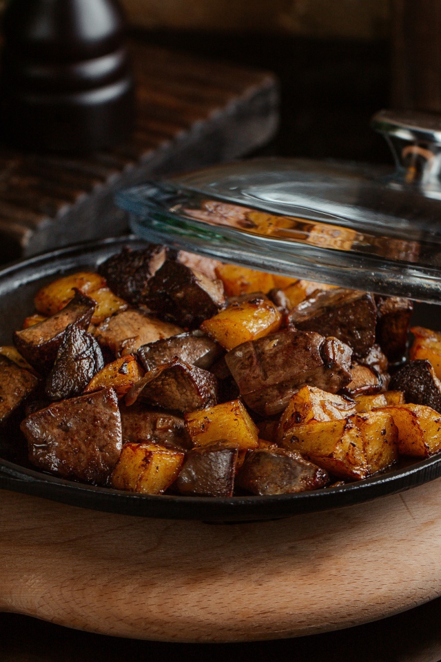 Печень с картофелем в сковороде на столе