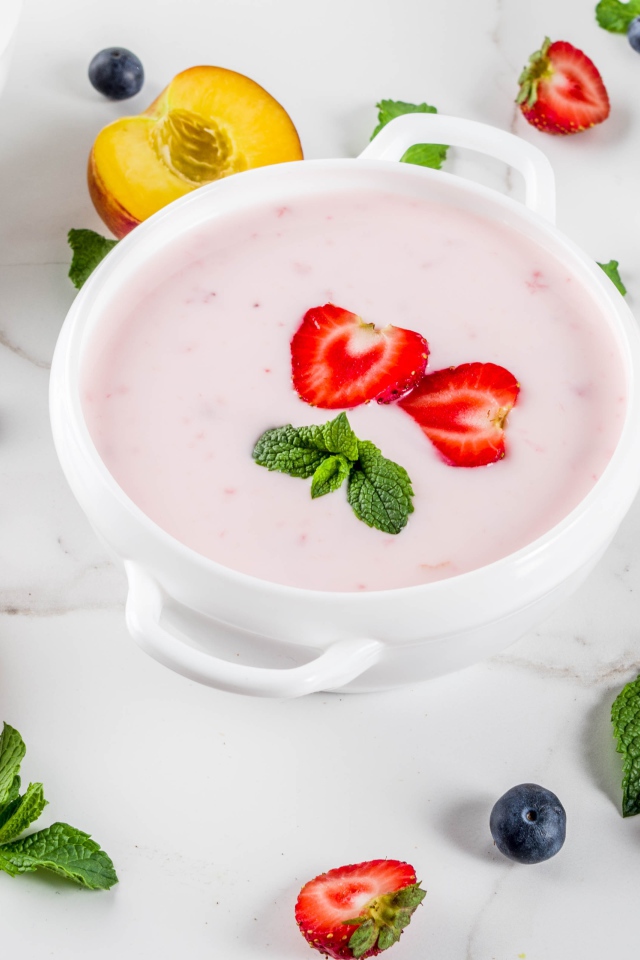 Молочный суп в тарелке на столе с ягодами и нектарином