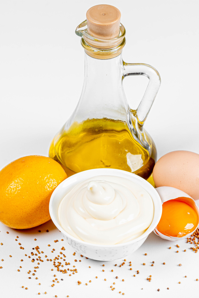 Оливковое масло, яйца и лимон на белом фоне с майонезом