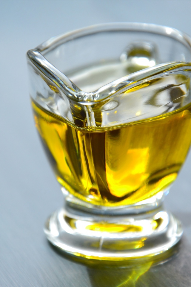 Оливковое масло в стеклянной вазе на столе 