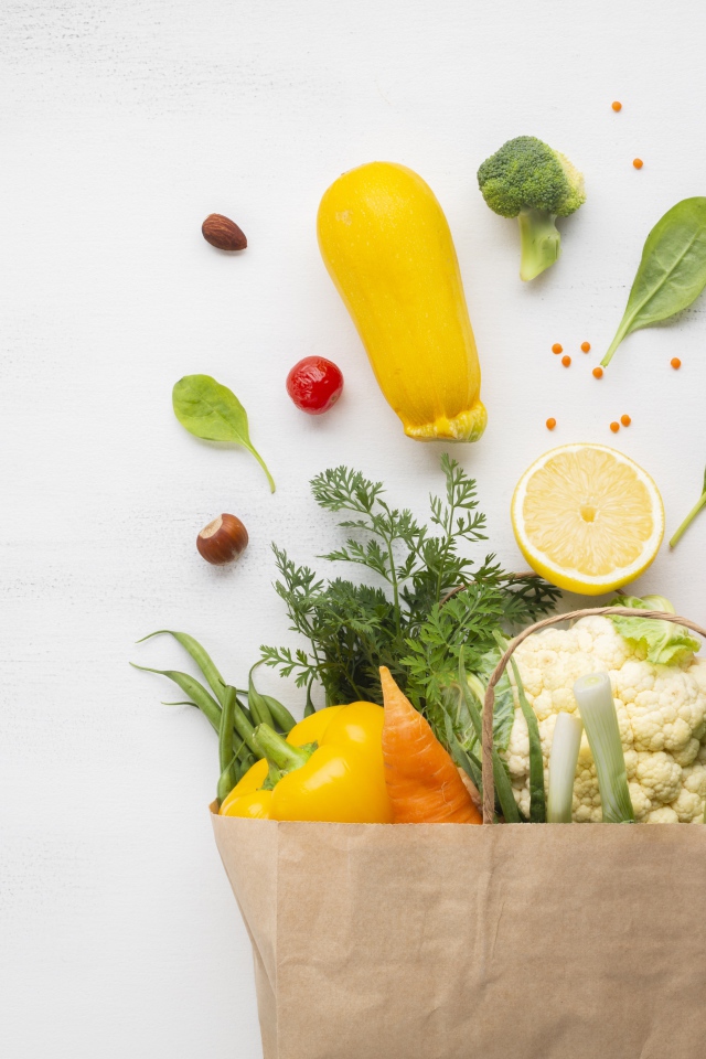 Пакет со свежими овощами и зеленью на сером фоне 