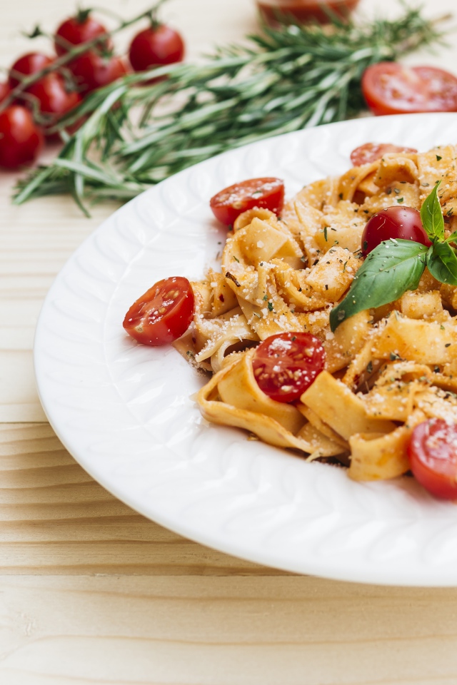 Паста с помидорами черри на белой тарелке