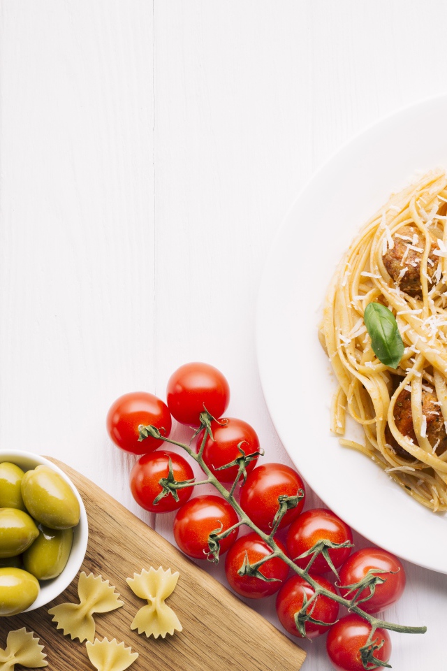 Паста с фрикадельками на столе с помидорами и оливками