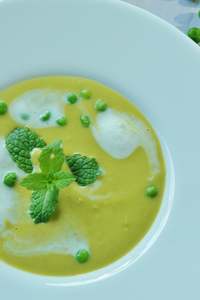 Суп пюре с зеленым горошком в белой тарелке 